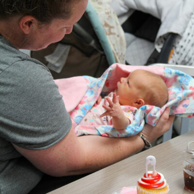 A woman smiles at a newborn baby