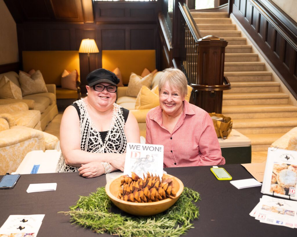 Two women in front of a table full of items