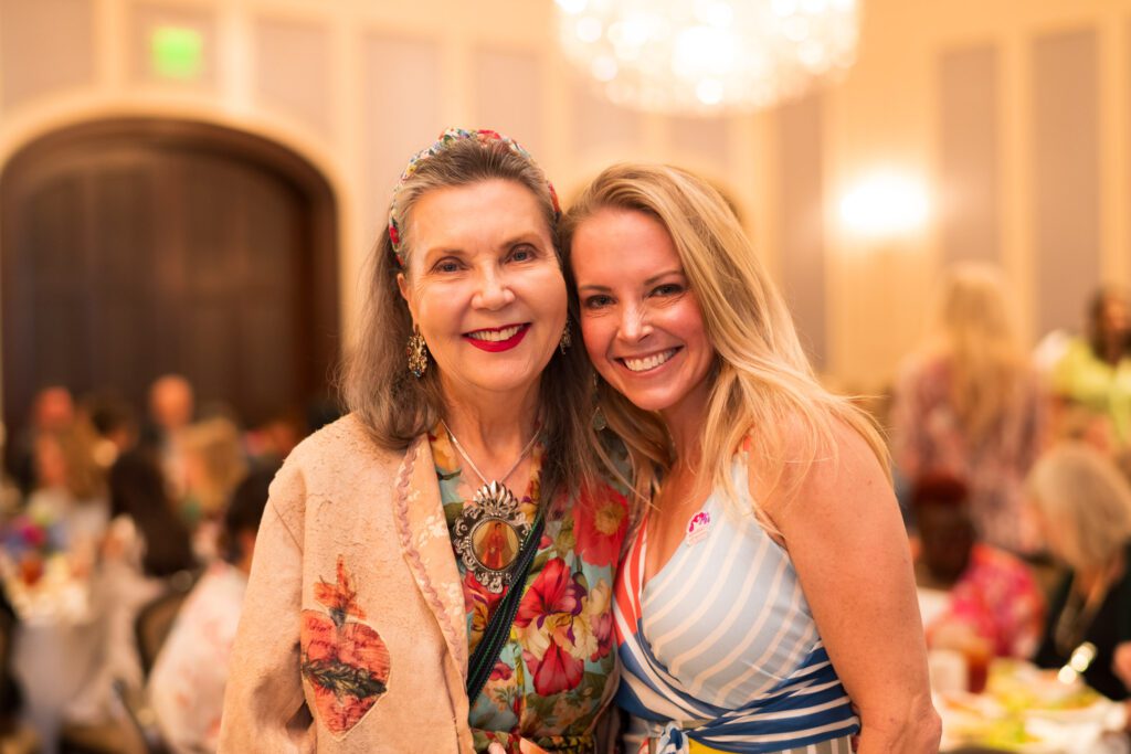 Two women in a ballroom embracing and smiling