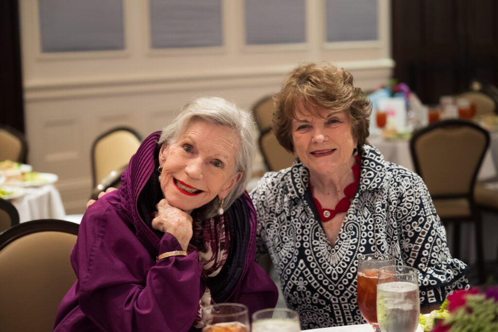 Two women at a luncheon table smiling