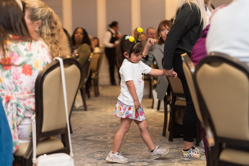 Child in a dining room wearing a bee antennae headband