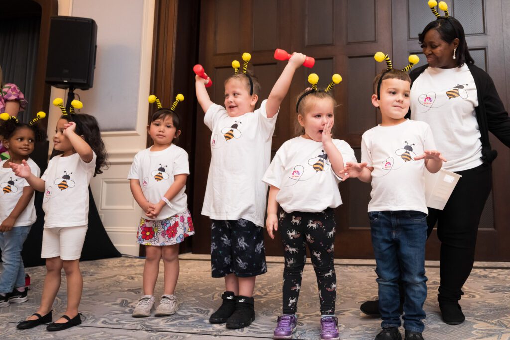 Children in bee antennae headbands dancing