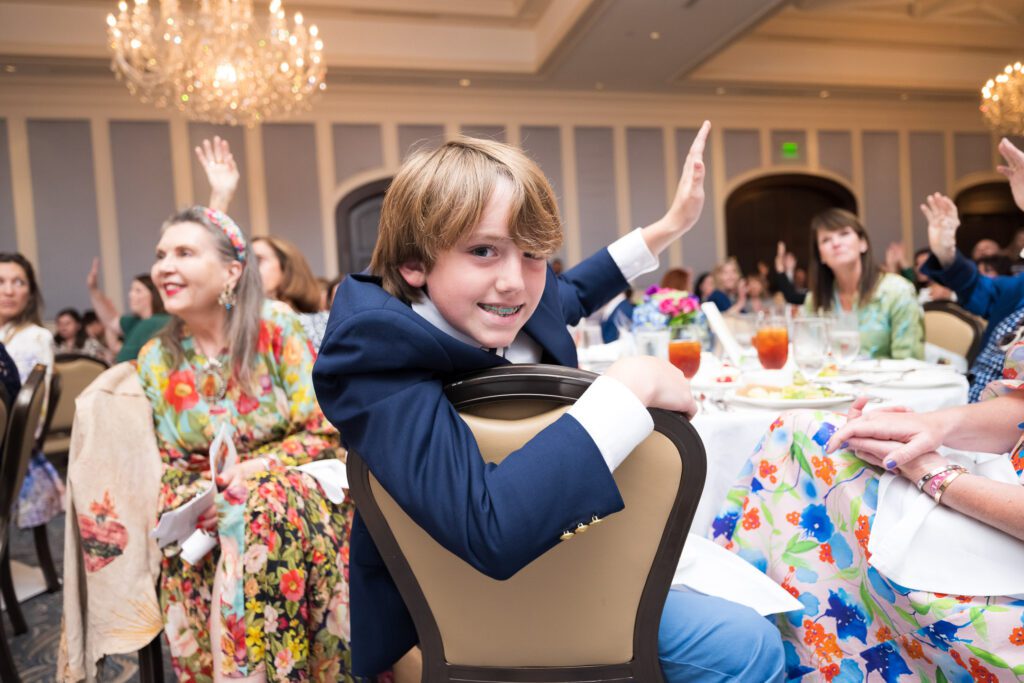 Child in a suit raising his hand