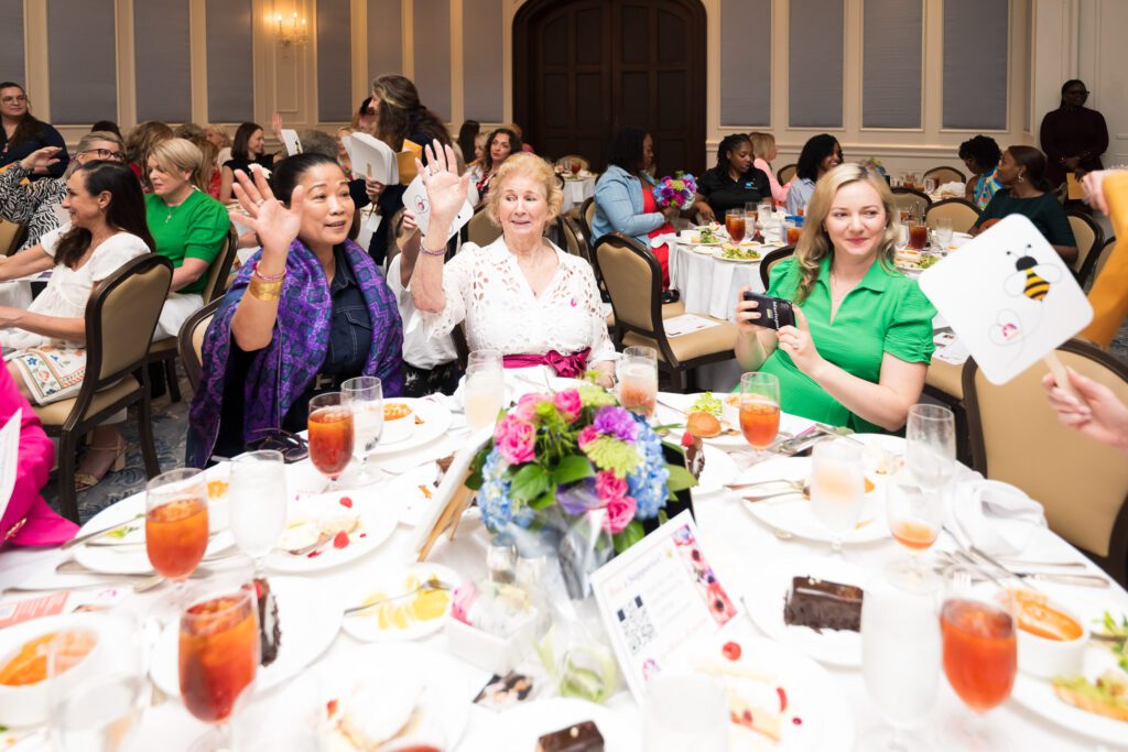 Women at a luncheon raising bidding paddles