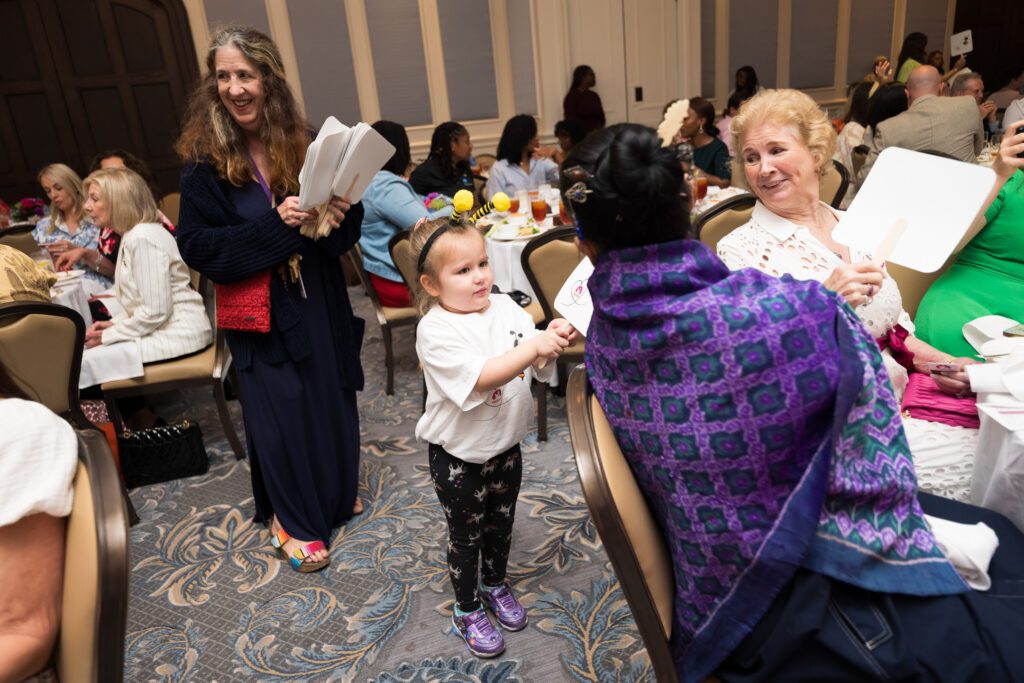 Child handing out bidding paddles to women