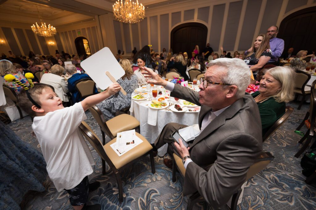 Luncheon guests raising bidding paddles