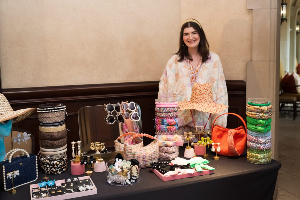 Woman standing with table of jewelry and sunglesses