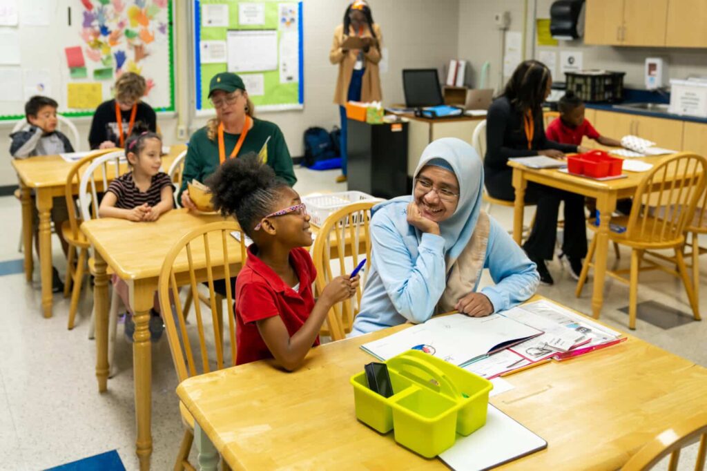 Classroom of students and teachers at desks with books