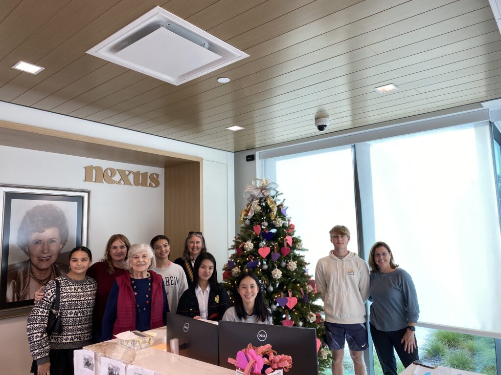 Volunteers from Paper for Water next to the holiday tree they sponsored and decorated in the Nexus Doswell Medical Building.